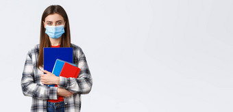 冠状病毒流感大流行科维德教育回来学校概念年轻的女学生医疗面具持有笔记本电脑类大一新生大学个人保护口罩
