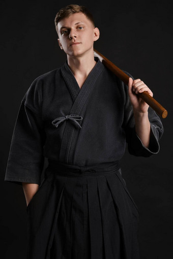 剑道老师穿传统的日本和服练习武术艺术shinai竹子剑黑色的工作室背景