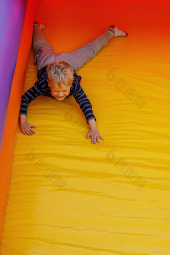 男孩积极玩孩子们的充气蹦床幻灯片胃明亮的红黄颜色免费的复制空间