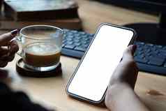 关闭视图女人持有咖啡杯模型聪明的电话空白屏幕图形显示蒙太奇