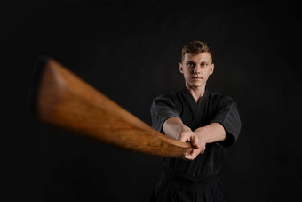 剑道老师穿传统的日本和服练习武术艺术shinai竹子剑黑色的工作室背景
