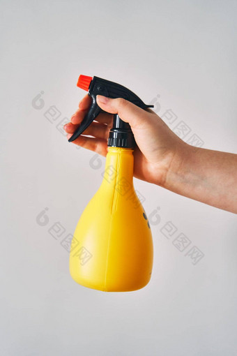 年轻的女人持有喷雾瓶手黄色的喷雾瓶白色背景