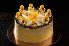 轮黄色的生日蛋糕装饰奶油装饰蛋糕黑色的背景