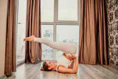 年轻的运动有吸引力的女人练习瑜伽作品首页瑜伽工作室运动服装白色裤子全身的前在室内健康的生活方式概念