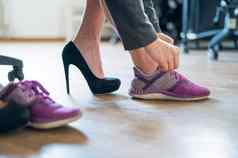 特写镜头腿办公室女员工脚疼痛女人高黑色的仿麂皮高跟鞋舒适的鞋子女孩需要鞋子把紫色的运行鞋子