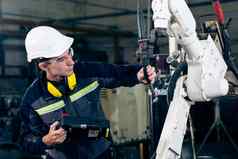 年轻的工厂工人工作熟练的机器人手臂