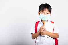 亚洲学生孩子男孩穿学生泰国统一的医疗保护脸面具拥抱请注意