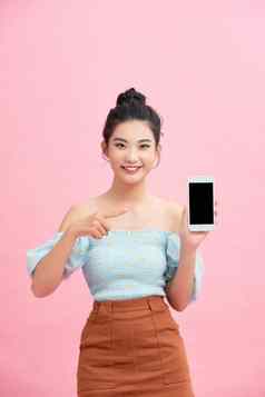 肖像兴奋年轻的女人显示空白屏幕移动电话孤立的粉红色的背景