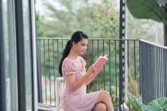 美丽的年轻的女人阅读书阳台