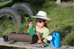 女孩穿他帮助妈妈。花园园丁可爱的女孩种植花锅出售家庭小业务