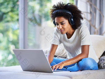 <strong>走向世界</strong>一天在线拍摄年轻的女人坐着首页移动PC穿耳机