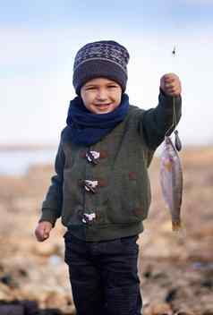 最大的抓肖像可爱的男孩持有鱼抓住了