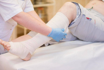 护士绷带腿骨折人类较低的四肢治疗破碎的骨头<strong>实施</strong>石膏病人外科手术部门医生的手收紧绷带腿