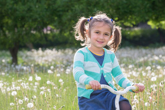 快乐的女孩自行车婴儿玩绿色草地五年婴儿蒲公英