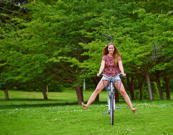 随心所欲的有趣的拍摄年轻的女人骑自行车公园