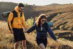 快乐的女人的男朋友持有手徒步旅行山日落年轻的夫妇享受旅行