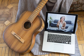爱好休闲活动检疫在线培训类年轻的女人手表视频教训玩电吉他坐在舒适的格子吉他组合Amp