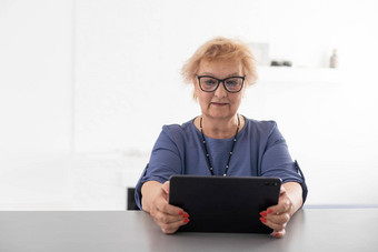 快乐成熟的中年女人花休闲时间首页数字平板电脑快乐的现代高级夫人持有电脑看有趣的电影笑着说休闲技术概念