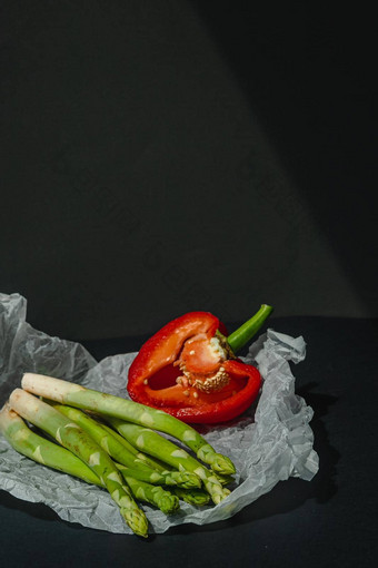 新鲜的绿色芦笋一半红色的甜蜜的大胡椒谎言白色羊皮纸黑暗灰色的背景适当的营养生活方式的地方文本