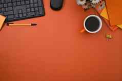 前视图时尚的工作空间无线键盘咖啡杯笔记本电脑橙色背景