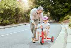 快乐父亲教学女孩骑自行车可爱的高加索人孩子穿粉红色的头盔骑自行车成键爸爸