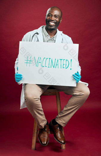 非洲美国科维德医生持有显示<strong>海报</strong>完整的<strong>长</strong>度肖像微笑黑色的医生孤立的红色的工作室背景Copyspace男人。促进电晕疫苗标志