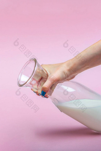 壶牛奶粉红色的背景女人的手牛奶玻璃瓶空间文本大横幅