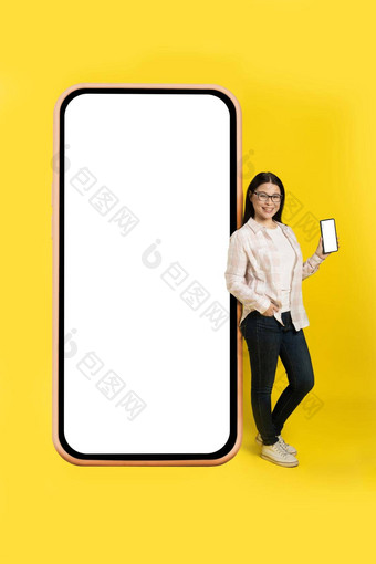 迷人的中间岁的亚洲女人电话手显示白色屏幕靠回来巨大的巨大的智能手机白色屏幕穿休闲孤立的黄色的背景免费的空间模拟