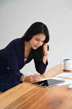 亚洲年轻的女人站办公室桌子上冲浪无线互联网数字平板电脑