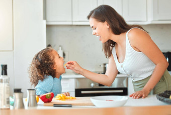 妈妈。喂养孩子蔬菜烹饪厨房妈妈告诉女儿开放宽吃蔬菜