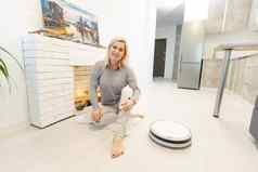 年轻的女人自动真空更清洁的清洁地板上控制聪明的机做家务机器人
