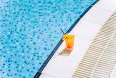 热带闪闪发光的鸡尾酒池拍摄玻璃橙色柠檬水水果鸡尾酒站在游泳池边夏天酒精免费的喝酒店池夏天假期假期