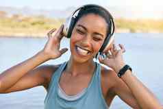 兴奋女人微笑听音乐水背景快乐年轻的女享受曲调在线流媒体播放列表在户外无线耳机玩歌曲