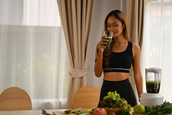健康的女人喝绿色排毒蔬菜奶昔健康的生活方式概念