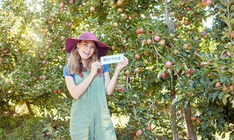 女农民招聘工人启动快乐年轻的女人持有招聘标志农场关闭苹果果园农场劳动短缺农业工作市场就业