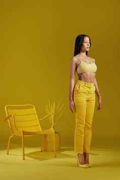 站选择工作室拍摄年轻的女人穿着时尚的黄色的衣服黄色的背景