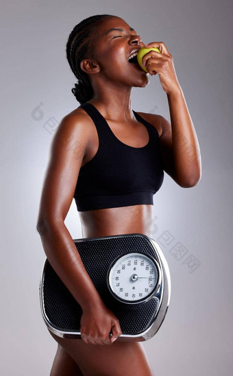 健康的吃常规的锻炼失去重量安全工作室拍摄运动年轻的女人吃苹果持有规模灰色背景