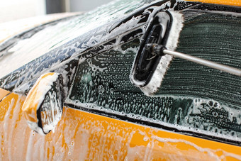 一边窗口黄色的车洗服务洗车刷离开中风玻璃覆盖洗发水泡沫
