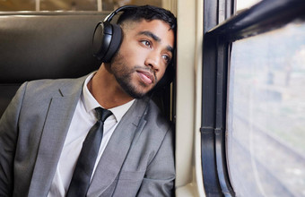 深沉思上下班年轻的商人穿耳机盯着窗口火车上下班