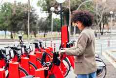 年轻的女人采取自行车租赁站