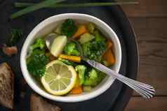 素食者蔬菜汤胡萝卜西兰花欧芹光碗金属托盘木表格