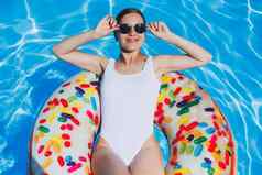 纤细的女人白色泳衣太阳镜谎言池充气圆夏天休息