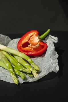 新鲜的绿色芦笋一半红色的甜蜜的大胡椒谎言白色羊皮纸黑暗灰色的背景适当的营养生活方式的地方文本