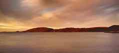 遥远的海景观山小帆船水海洋海滩大湖船距离山在户外日落多云的一天