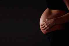 怀孕了女人感觉婴儿黑色的Copyspace中期部分怀孕了女人感觉婴儿黑色的背景Copyspace