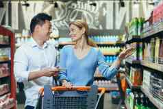 快乐购物者亚洲男人。女人买选择货物超市家庭购物