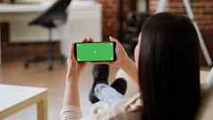女人坐着沙发持有智能手机绿色屏幕模型模板背景