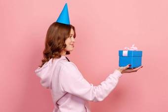 配置<strong>文件</strong>快乐卷曲的头发的十几岁的女孩连帽衫聚会，派对帽<strong>展示</strong>蓝色的包装礼物盒子假期