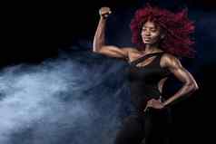 运动美丽的美国黑人模型女人运动服装使健身锻炼黑色的背景保持适合