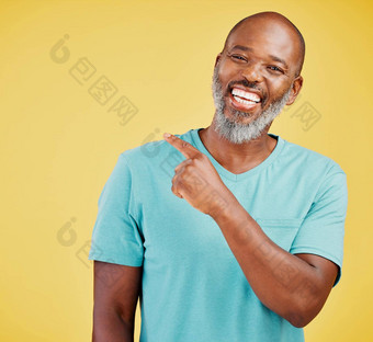 成熟的非洲男人。笑指出方向黄色的工作室背景黑色的的家伙咯咯地笑使指出手势反应笑声快乐的快乐减轻情绪有趣的有趣的笑话